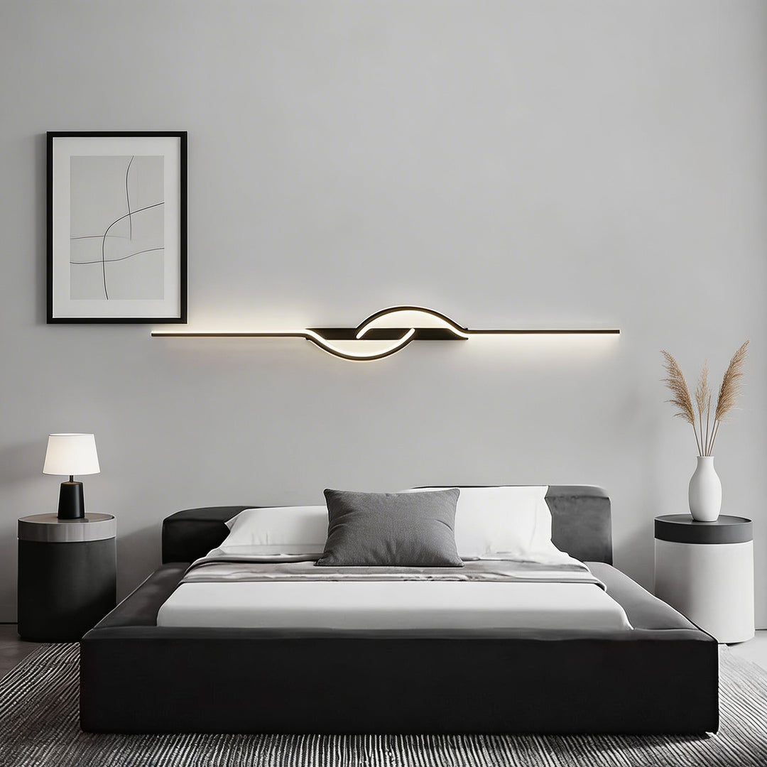 Long black horizontal LED wall sconce with warm centre loop above black platform bed, minimalist bedroom wall light Australia