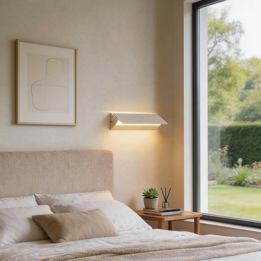 White angled fold LED wall sconce with warm downward glow beside bed, minimalist bedside reading wall light Australia