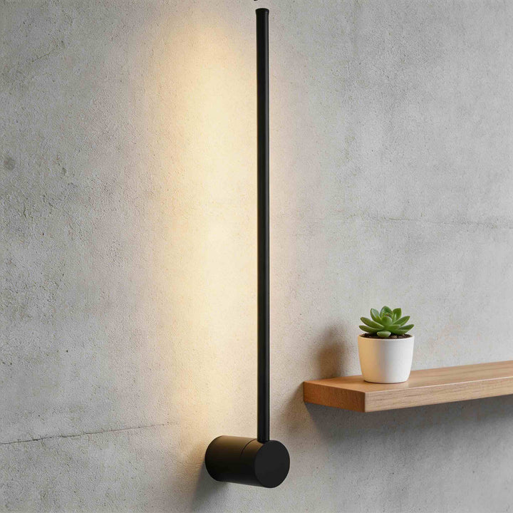 Wall sconce in matte black with slim vertical rod and round base, minimalist LED wall light with warm ambient glow and modern design